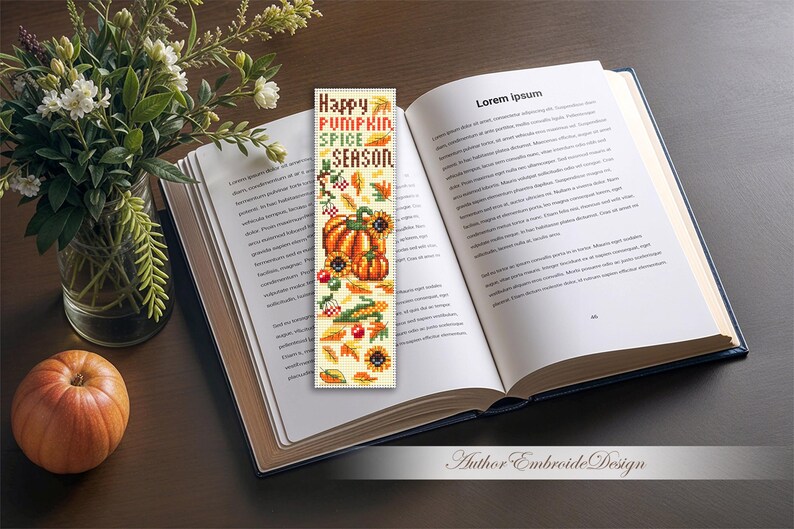 May include: A bookmark with the text "Happy Pumpkin Spice Season" and autumn-themed illustrations of pumpkins, sunflowers, and leaves. The bookmark is placed in an open book next to a small pumpkin and a vase of flowers.