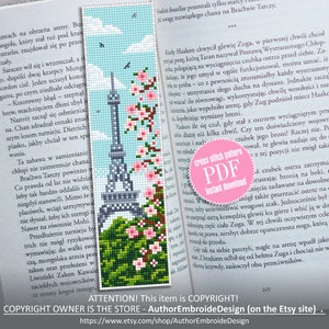 May include: A cross stitch pattern PDF for a bookmark featuring the Eiffel Tower in Paris, France. The tower is gray and black, with a green base and pink flowers. The text "cross stitch pattern PDF instant download" is on a pink circle.