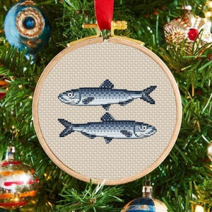 May include: A wooden hoop ornament with a beige fabric background featuring two blue and white embroidered fish.