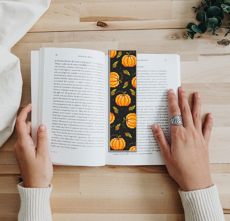 May include: A black and orange beaded bookmark with a pattern of pumpkins and leaves. The bookmark is about 10 inches long.
