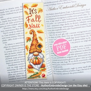Puede incluir: Un marcapáginas de punto de cruz con un gnomo sosteniendo una calabaza, con el texto "It's Fall y'all". El marcapáginas tiene hojas de otoño y un diseño de girasol. El marcapáginas está colocado en un libro abierto.
