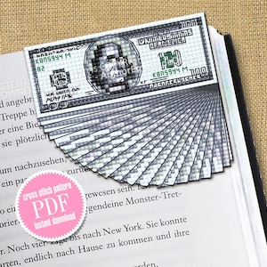 Może przedstawiać: Wzór do haftu krzyżykowego w formacie PDF na zakładkę przedstawiającą stos banknotów 100-dolarowych. Zakładka wykonana jest z szarych i białych kwadratów. Tekst "cross stitch pattern PDF instant download" znajduje się na różowym kole.
