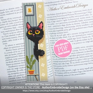 May include: Cross-stitch bookmark featuring a black cat with yellow eyes, a small plant, and a picture frame. The bookmark is set against a book page. The text "Author Embroide Design" is visible.