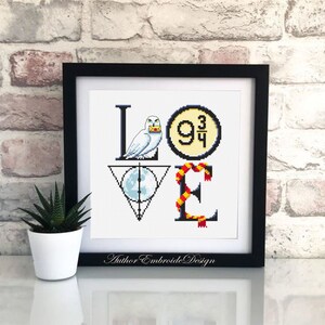 May include: A white cross-stitch embroidery design featuring the word "LOVE" with Harry Potter themed icons. The "L" features a white owl holding a letter, the "O" features the platform 9 3/4 sign, the "V" features the Deathly Hallows symbol, and the "E" features a red and gold scarf.