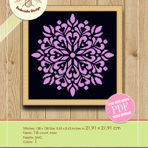 May include: A framed counted cross stitch pattern featuring a symmetrical floral design in shades of pink on a black background. The pattern is 8.63 x 8.63 inches (21.91 x 21.91 cm) and available for instant download.