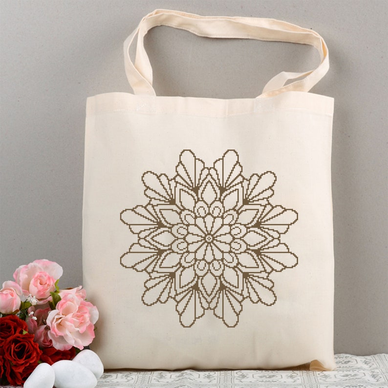 May include: A white canvas tote bag with a brown mandala design printed on the front.