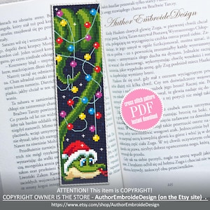 May include: A cross stitch pattern featuring a green Christmas tree with colorful lights and a green frog wearing a red Santa hat. The pattern is available as a PDF download. The text "cross stitch pattern PDF instant download" is on a pink circle.