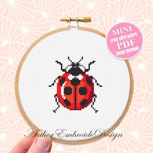 May include: A cross stitch pattern of a red ladybug with black spots. The pattern is in a wooden embroidery hoop and is labeled "MINI cross stitch pattern PDF instant download".