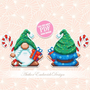Puede incluir: Patrón de punto de cruz PDF de descarga instantánea de dos gnomos con gorros de árbol de Navidad, sosteniendo bastones de caramelo y regalos. Los gnomos están sobre un fondo rosa con un patrón geométrico blanco.