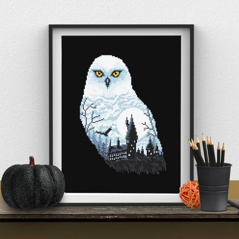 Pu&ograve; includere: Un gufo delle nevi bianco con occhi gialli, con una silhouette del castello di Hogwarts all'interno del corpo del gufo. Lo sfondo &egrave; nero.