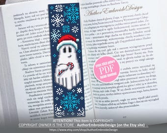 Könnte beinhalten: Ein Kreuzstichmuster für ein Lesezeichen mit einem weißen Geist, der einen Zuckerstock vor einem blauen Hintergrund mit Schneeflocken hält. Der Text "cross stitch pattern PDF instant download" befindet sich in einem rosa Kreis.