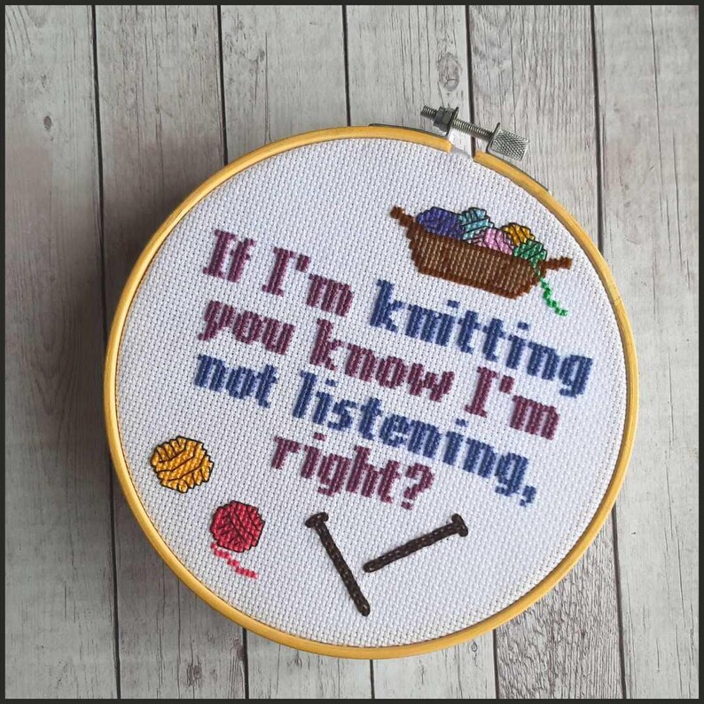 May include: White embroidery hoop with a yellow wooden frame. The embroidery reads "If I'm knitting, you know I'm not listening, right?" with a basket of yarn, two knitting needles, and two balls of yarn.