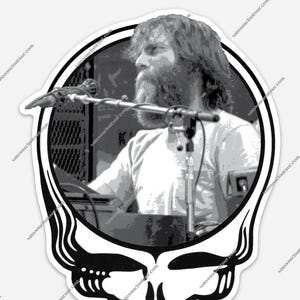 May include: Black and white sticker featuring a musician with a long beard and microphone, set within a skull and oval frame. The skull has a detailed, stylized design. The background shows a stage setting.