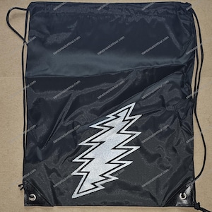 May include: Black drawstring bag with a silver lightning bolt graphic. The bag has a white drawstring and a white logo on the front.