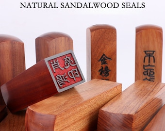 May include: A collection of five natural sandalwood seals with intricate carvings. The seals are rectangular in shape and have a reddish-brown color. The text on the seals reads "金榜" and "官運亨通".