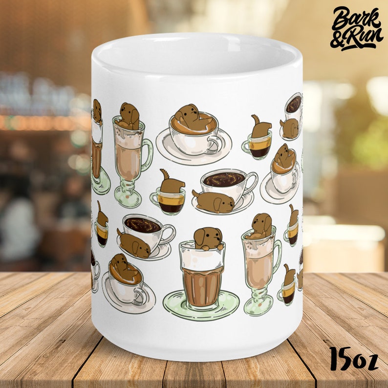 May include: White ceramic coffee mug with a design of brown dogs in various coffee cups and mugs. The mug has the text "Bark & Run" and "15oz" printed on it.