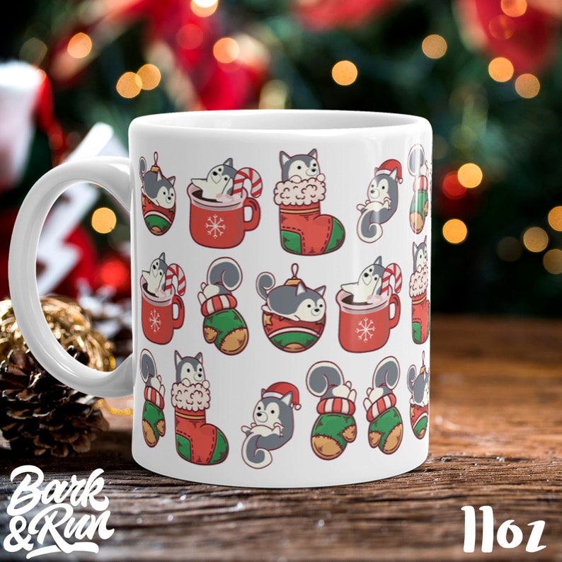 May include: White ceramic mug with a Christmas-themed design featuring a pattern of cartoon huskies in various holiday settings, including a stocking, a mug of hot chocolate, and a Christmas ornament. The mug is 11 oz.