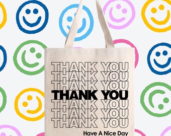 May include: A white canvas tote bag with black text that reads "THANK YOU" repeated multiple times. The text is in a retro style font. The bag also has the text "Have A Nice Day" printed on the bottom.