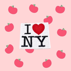 Könnte beinhalten: Weißer Patch mit dem Text "I love NY" in schwarzen Buchstaben und einem roten Herzen. Der Patch ist von rosa Äpfeln umgeben.