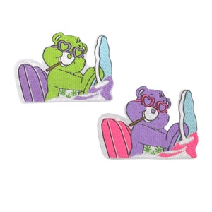 May include: Two embroidered iron-on patches featuring cartoon bears wearing heart-shaped sunglasses and holding a joint. The bears are riding on surfboards with a wave design. One bear is green and the other is purple.