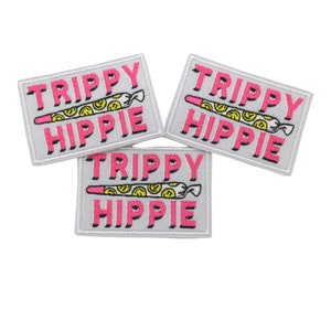 May include: Three iron-on patches with a white background and pink text that reads "Trippy Hippie". Each patch features a cartoon drawing of a joint with smiley faces.