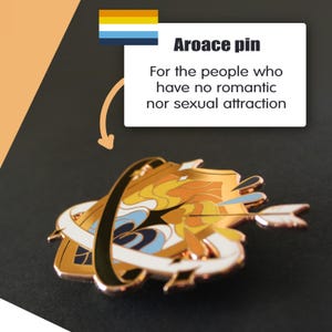 May include: Aroace pin with a gold, white, and blue design. The pin features an arrow and a stylized shape. Text on the image reads "Aroace pin" and "For the people who have no romantic nor sexual attraction."