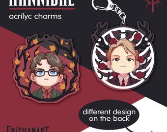 Puede incluir: Dos dijes de acrílico con personajes ilustrados. Uno muestra a una persona con cabello castaño y gafas rodeada de ramas oscuras y hojas amarillas. El otro muestra a una persona con cabello rubio, astas y rosas rojas, unido a un llavero plateado.