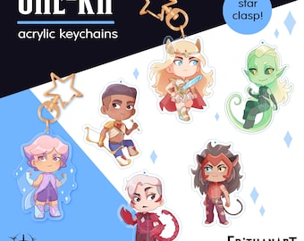 Op de afbeelding: Een collectie She-Ra acryl sleutelhangers met zes verschillende karakterontwerpen. Elke bedel is voorzien van een goudkleurige, stervormige sluiting. De personages zijn afgebeeld in een gestileerde, chibi-geïnspireerde kunststijl met levendige kleuren.