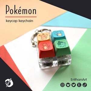 May include: A keycap keychain featuring four colorful keycaps with Pokémon character designs. The keycaps are red, orange, blue, and green, with a clear plastic base and a silver keychain ring. The word "Pokémon" is written at the top.