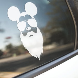 Puede incluir: Calcomanía de vinilo blanco de un ratón de dibujos animados con gafas de sol y barba, aplicada a la ventana de un coche. El diseño presenta las icónicas orejas del ratón y una barba estilizada.