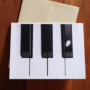 Carte de correspondance Plume blanche sur les touches du piano 4,25 x 5,5 po.