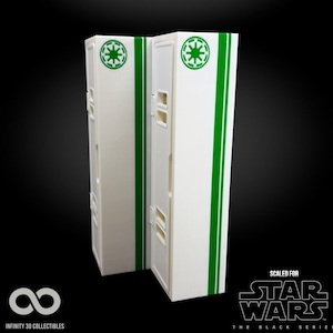 May include: Two white rectangular boxes with green stripes and circular logos, likely for Star Wars collectibles. The boxes have a series of small rectangular cutouts. The words "SCALED FOR STAR WARS THE BLACK SERIES" are printed on the bottom right.