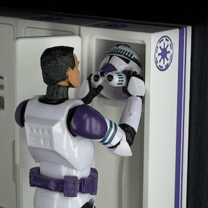 May include: A white and purple action figure of a character from a science fiction franchise. The figure is holding a white and purple helmet. The figure is in a white cabinet with a purple stripe and a symbol.