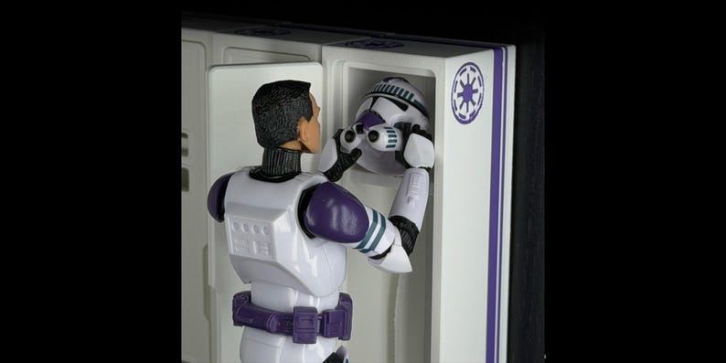 May include: A white and purple action figure of a character from a science fiction franchise. The figure is holding a white and purple helmet. The figure is in a white cabinet with a purple stripe and a symbol.