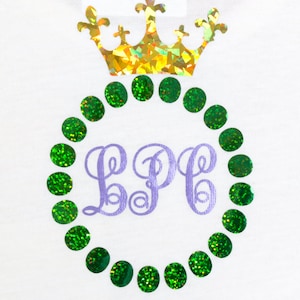 May include: A white t-shirt with a purple monogram "LPP" surrounded by a circle of green glitter dots. A gold glitter crown sits above the monogram.