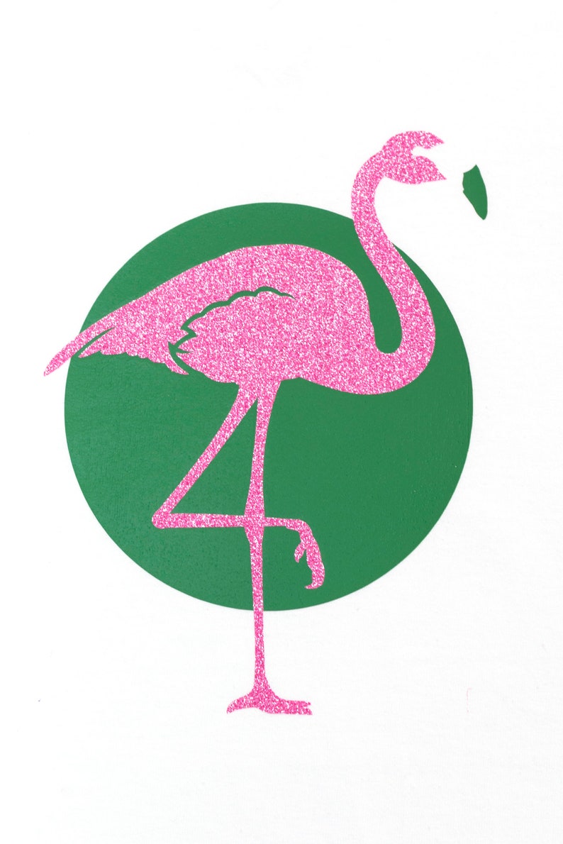 Op de afbeelding: Pink glitter flamingo silhouet staand op &eacute;&eacute;n been tegen een groene cirkel achtergrond.