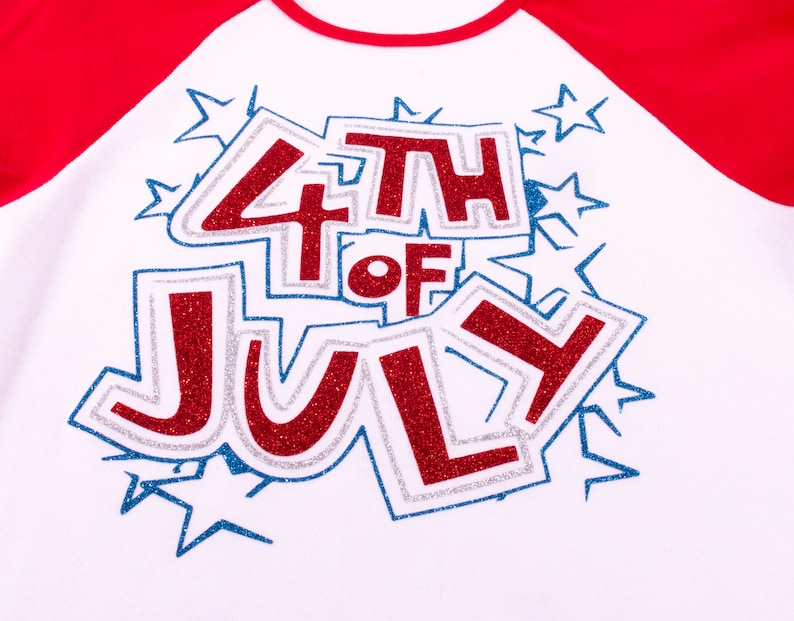 May include: A white raglan shirt with red sleeves featuring a glittery red and blue graphic that reads 4TH OF JULY. The text is surrounded by blue glitter star outlines and has a silver glitter border, creating a festive and bold appearance.