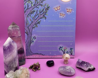 May include: A purple and green notebook with a whimsical illustration of a tree, moon, and butterflies. The notebook has lined pages and is perfect for writing down thoughts, ideas, or dreams.