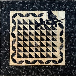 May include: Black and white quilt with a geometric pattern of triangles. The quilt is framed with a scalloped border and features a silhouette of a bird on a branch in the upper right corner.