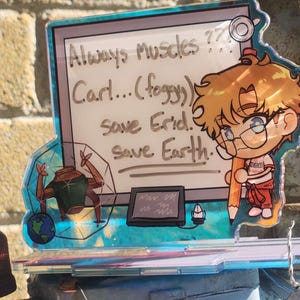 May include: A clear acrylic standee featuring a cartoon character with blonde hair holding a large pencil. The design includes a white board with the text Always Muscles ??? Carl... (foggy) Save Erid. Save Earth. and a small robot graphic.