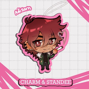 Puede incluir: Un charm rosa con una ilustración de dibujos animados de una persona con cabello rojo, que lleva una chaqueta verde y sostiene un cigarrillo. El charm tiene el texto "Adisorn" y "Charm & Standee".