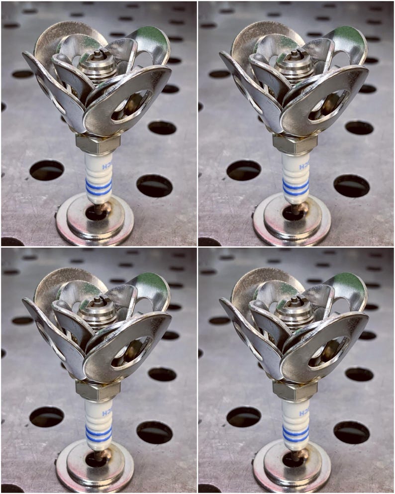 May include: Four metal roses made from spark plugs and washers. Each rose is silver and has a blue stripe on the spark plug.