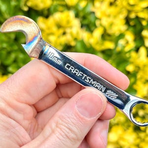 May include: A silver Craftsman wrench with a bottle opener on one end. The wrench is 1/4 inch.