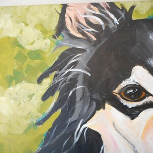 May include: Close-up of a black and white painting of a dog's face. The dog has a brown eye and a white patch of fur on its face. The background is a yellow-green colour.