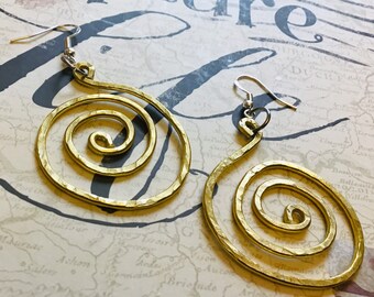 May include: A pair of gold-toned spiral earrings. The earrings are made of hammered metal and have a simple, modern design.