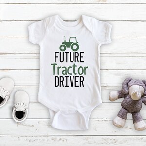 May include: White baby onesie with a green tractor graphic and the text "FUTURE TRACTOR DRIVER".