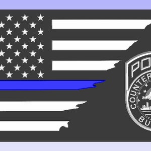 May include: A black and white American flag with a blue line running horizontally across the flag. The flag is torn on the right side, revealing a silver police badge with the words "Police Counterterrorism Bureau" and "NYPD 9/11" on it.