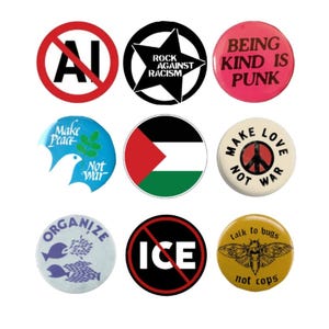 May include: A collection of nine circular pin-back buttons featuring various designs and text, including "No AI," "Rock Against Racism," "Being Kind Is Punk," "Make Peace Not War," a flag, a peace sign, "Organize," "No ICE," and "Talk to bugs not cops."