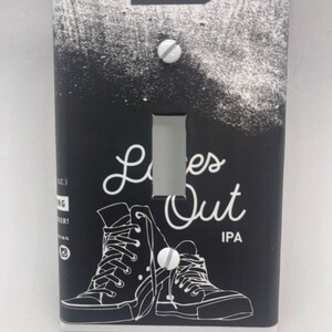 May include: Black and white light switch cover with a graphic of two sneakers and the text "Laces Out IPA" with the words "Mumford Brewing" at the top.