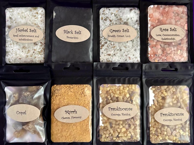 Puede incluir: Ocho bolsas negras con ventanas transparentes que contienen diversas sales y resinas. Las etiquetas incluyen Herbal Salt, Black Salt, Green Salt, Rose Salt, Copal, Myrrh y Frankincense, cada una con texto descriptivo en pegatinas ovaladas.